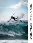 Small photo of Young surfer with with wetsuit enjoying big waves in Tenerife, Canary Islands. Sporty boy riding his surf board on the ocean wave. Brave teenager making tricks on the rough sea during a competition.