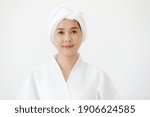 Portrait of middle age Asian woman with towel-covered around her head in the spa. She is smiling and looking at camera. Idea for female who care for health and skin.