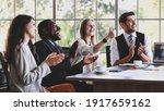 Small photo of Group of four professional multiethnic businessmen and businesswomen sitting, clapping hands and showing thump up gesture to celebrate the new project in company meeting at office working table