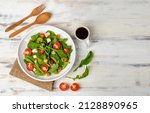 Small photo of Fresh spinach salad with tomato, small pieces of herb roasted chicken in white ceramic dish on brown sackcloth, together with balsamic vinegar and utensil on white wooded table. Concept for healthy.