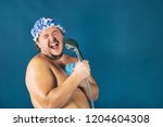 Funny fat man in blue cap sing in the shower. Fun and cleanliness
