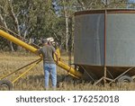 Small photo of a farmhand checking motor on auger closeup