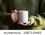Female hand holding white mug...