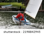 Small photo of Staines-upon-Thames, UK September 4th 2022 A man in a sailing dinghy on the River Thames. Heeled boat, stern view