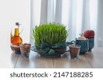 Small photo of Iranian haft seen, green wheat grass,apple,sumac powder,garlic, vinegar,coins and senjed in the blue Plates,Traditional celebration of spring in March, Nowruz Holiday,Cultural feast.copy space.