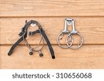 Steel horse snaffle-bit and spurs, hanging on wooden background. Outdoors close-up image.