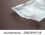 Small photo of Small transparent plastic bag with zip clasp on a dark background. The clasp is open.