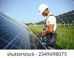 Small photo of African american man in safety helmet and glasses tighten nuts on solar panels with screwdriver. Competent technician using tools while performing service work on station.