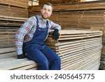 Small photo of Industrial warehouse of a sawmill, an employee puts his hands on the finished products at the sawmill in the open air