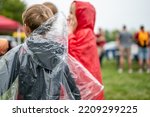 Small photo of Young child with a clear plastic poncho to keep off the rain at a football game.