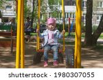Small photo of Baby girl sleeps on the swing, tired child is seasick on the swing in the playground.