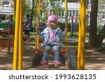 Small photo of Baby girl sleeps on the swing, tired child is seasick on the swing in the playground.