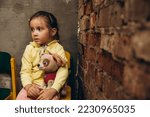 Small photo of 07.07.22 Irpin, Ukraine: portrait of a little girl sitting in an underground cellar during evacuation after an air raid siren in Ukraine