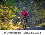Small photo of sympathetic active senior woman, riding her electric mountainbike in the colorful autumn forests of the Bavarian Alps near Oberstaufen, Germany