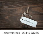 Small photo of The key of dissension concept isolate. Silver key with a label on wood table.