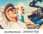 Freedom of the open road. Side view of joyful young woman relaxing on the front seat while her boyfriend sitting near and driving their convertible 