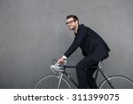 Keep calm and ride on. Cheerful young businessman smiling and looking away while cycling against grey background