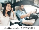 Enjoying travel. Beautiful young couple sitting on the front passenger seats and smiling while handsome man driving a car