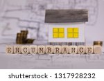 Small photo of Word ENCUMBRANCE composed of wooden letters. Small paper house in the background. Closeup