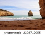 Waves in Atlantic Ocean with limestone cliffs on a sandy beach along the Seven Hanging Valleys Trail in southern Portugal on a sunny winter day.