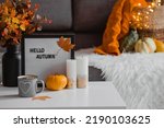 Small photo of Cozy autumn concept. Home warmth in cold weather. Still-life. A blanket, pumpkins, flowers and a cup of tea on the coffee table in the living room home interior.