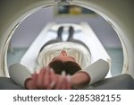 Small photo of A young pretty girl is undergoing a CT scan in a medical clinic. Computed tomography scanning of the body. Prevention illness. Early detection of cancer.