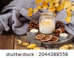 Autumn composition with aromatic candle, dry citrus, cinnamon. Aromatherapy on a grey fall morning, atmosphere of cosiness and relax. Wooden background close up