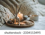 Small photo of Apartment natural aroma diffusor with sea breeze fragrance. Burning candles on bamboo tray, cozy home atmosphere. Relaxation, detention zone in the living or bedroom. Stones as decor