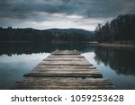 Mole (pier) on the lake.  Wooden bridge in forest in spring time with blue lake. Lake for fishing with pier. Dark and  Foggy lake with hills.