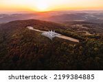 Small photo of Aerial photo by drone of The Barrow (cairn) of Milan Rastislav Stefanik upon Hill with beautiful green trees around - on sunset. top view of The Barrow of Stefanik on sunset - golden hour.