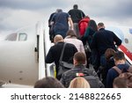 Small photo of People climb the ramp to the plane. Passengers are loaded into the aircraft. People go up the stairs to the cabin of air transport. Event at the airport.