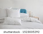 Small photo of White pillows, duvet and duvet case on a blue bed. White bed linen on a blue sofa. Bedroom with bed and bedding. Messy bed. Front view.