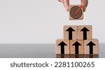 Small photo of Goal Achievement and Purposefulness,challenge in busiess concept.,Hand arranges a wooden block with dartboard icon stack in pyramid shape over white background with copyspace.