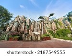 Small photo of A huge rockery built artificially, and the water flows down from the top of the rockery to form an artificial waterfall