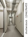 Small photo of LONG LIGHT CORRIDOR WITH IRON AND STEEL DOORS AND COMMUNICATIONS UNDER CEILING IN BASEMENT OF MODERN RESIDENTIAL BUILDING. Bomb shelter (shelter, bombproof shelter, bombshelter, air-raid shelter).