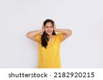 Small photo of young Asian woman on a white background holds her head closes her ears from stress and noise. concept of problem and difficult task, business. predicament fear and confusion
