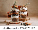 Two glasses with a layered dessert trifle with chocolate, cream, cookies and blueberries