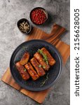 Small photo of Traditional south european skinless sausages cevapcici made of ground meat and spices on black plate on dark wooden board, with thyme and watercress salad