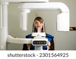 Small photo of Female patient having computer tomography of jaw, circular snapshot of jaw in modern dentistry in x-ray office. Computed 3d tomography of teeth and jaw. Panoramic scanner.