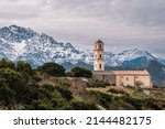 Small photo of Church in the hilltop village of Sant'Antonino in the Balagne region of Corsica with snow capped mountains in the distance