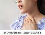 Small photo of Close up of woman coughing while she having sore throat problem. A sore throat is a painful, dry, or scratchy feeling in the throat.