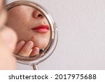 Small photo of Cropped shot of woman worry about her face when she saw the problem of acne occur on her chin by a mini mirror. Conceptual shot of Acne and problem skin on female face.