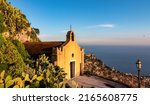Chiesa di San Biagio of Castelmola with panoramic view on coastline of Ionian Mediterranean sea near Taormina, Sicily, Italy, Europe, EU. A field of cactus around the church at sunset golden hour time