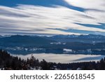 Panoramic view of the lake Woerthersee (lake Worth), tower Pyramidenkogel and snow capped Karawanks mountain range near Techelsberg, Carinthia (Kaernten), Austria, Europe. Winter wonderland in Alps