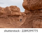 Small photo of Woman hiking next to unique eroded Hoodoo Rock Formations at Goblin Valley State Park in Utah, USA, America. Sandstone rocks called goblins which are mushroom-shaped rock pinnacles. Canyon hike trail