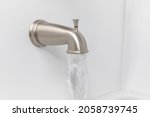 Small photo of Bathtub spout flowing water. Plumbing repair, bathroom remodel and renovation concept