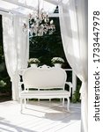 Small photo of In the garden there is terrace on which a white sofa in style of Provence or rustic. Beautiful sofa is on podium Outdoor. Summer gazebo with white curtains. Wedding decorations. Romantic alcove.