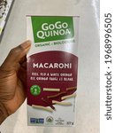 Small photo of Edmonton, Canada - April 20, 2021: A Black person holding a box of GoGo Quinoa Macaroni in a grocery store. GoGo Macaroni is a gluten free pasta alternative made from rice and red and white quinoa