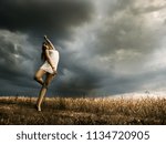 Young girl in white dress with dramatic sky background