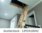 folding attic ladder. Wooden pull down attic folding stairs in small hallway, space saving in home concept